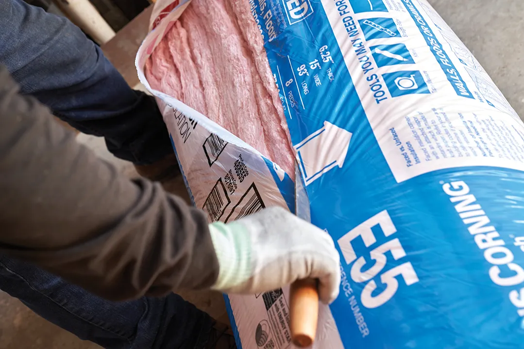 A Marshall's technician opens a package of pink fiberglass insulation material.