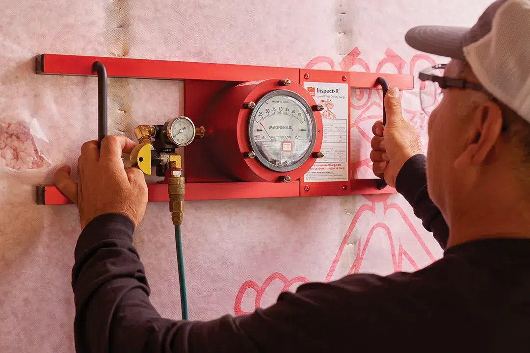 A Marshall's insulation expert inspects an insulation's depth with a red tool.