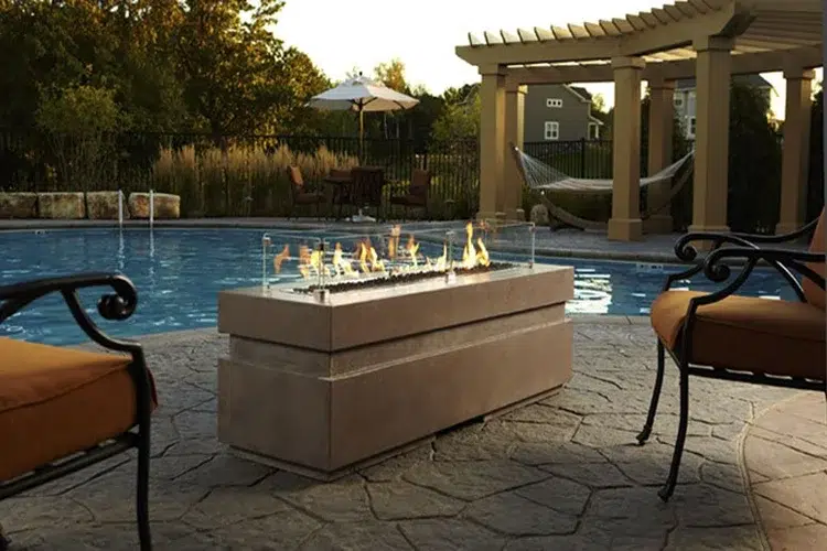 An image of an outdoor fireplace in front of a large pool.
