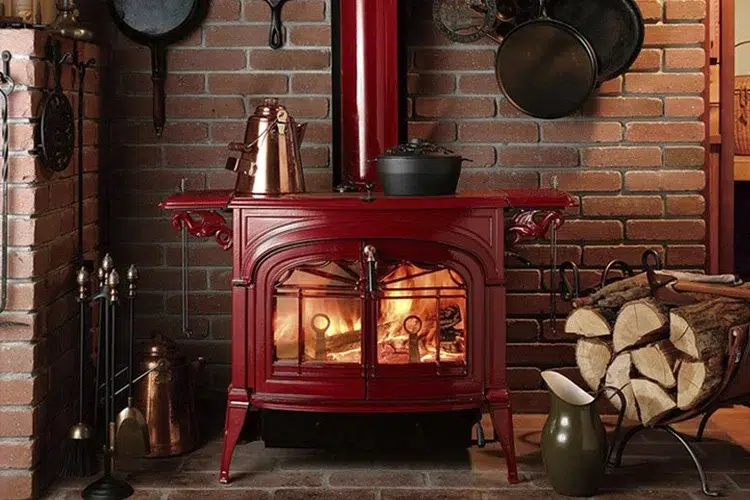 An image of a vintage red furnace unit with fire on the inside.
