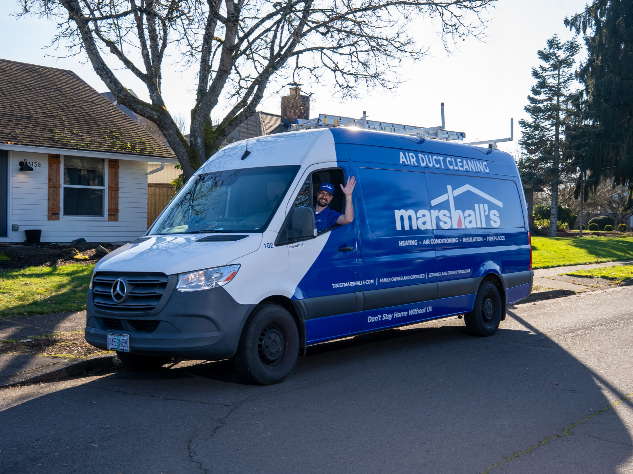 A Marshall's technician drives a work van in an Oregon neighborhood and waves to the camera.